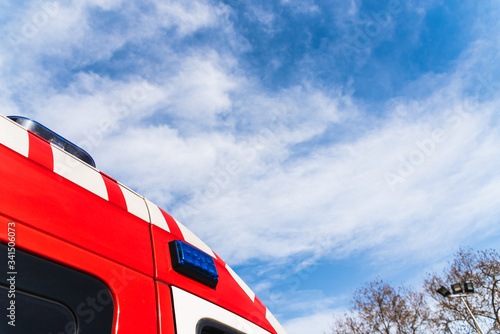 Red roof of a medicalized ambulance over blue sky with clouds and copy space, to care for pandemic sufferers. photo