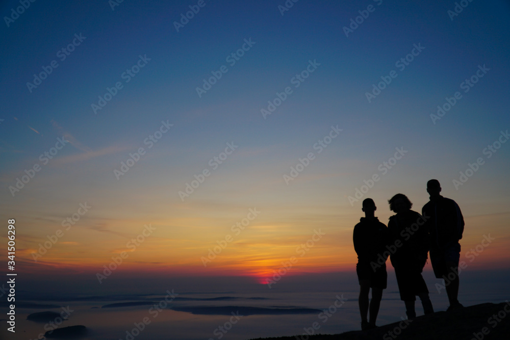 silhouette of family on mountain in sunrise