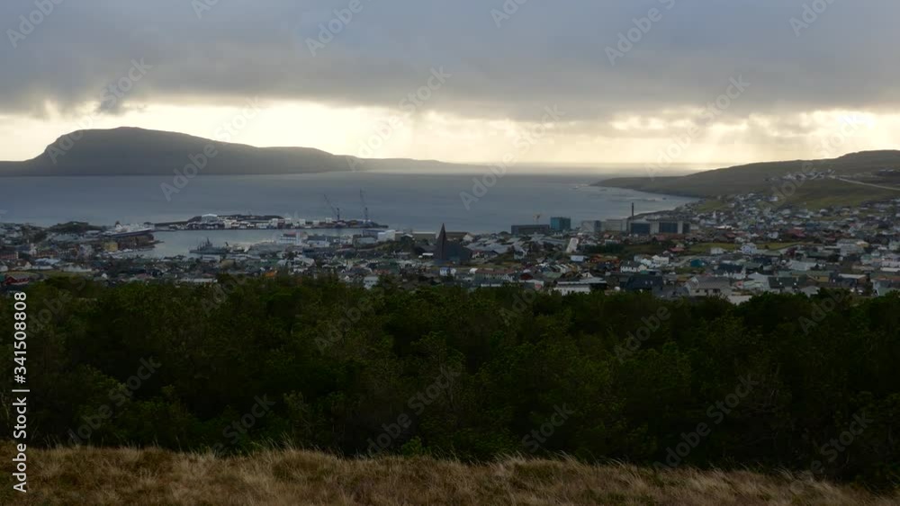 Long shot cityscape of the small town of Torshavn near sea and a big mountainous island in background Long shot cityscape of the small town of Torshavn near sea and a big mountainous island in background