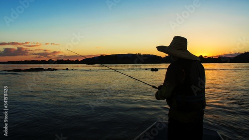 Fisherman silhouette, in Xingu River, amazon forest, Brazil. Fishing during sunset. High contrasts
