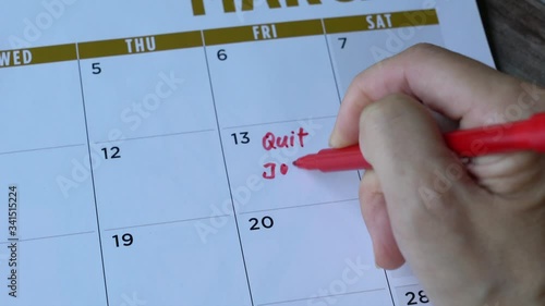 Woman writing quit job words with red marker pen on a calendar. Unemployment or frustration with job concept. 