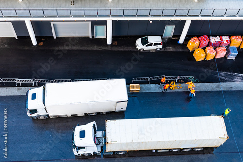 White 10 (ten) wheeler freight truck parked next to 18 (eighteen) wheeler delivery trailer on asphalt road inside shipping/ shipment delivery port. photo