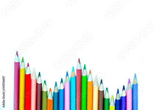 Photo of arrangement of color pencils isolated on white background. Blank space for text. Flat lay. Close up. Top view. Leadership business concept. School concept. Rainbow color pencil.