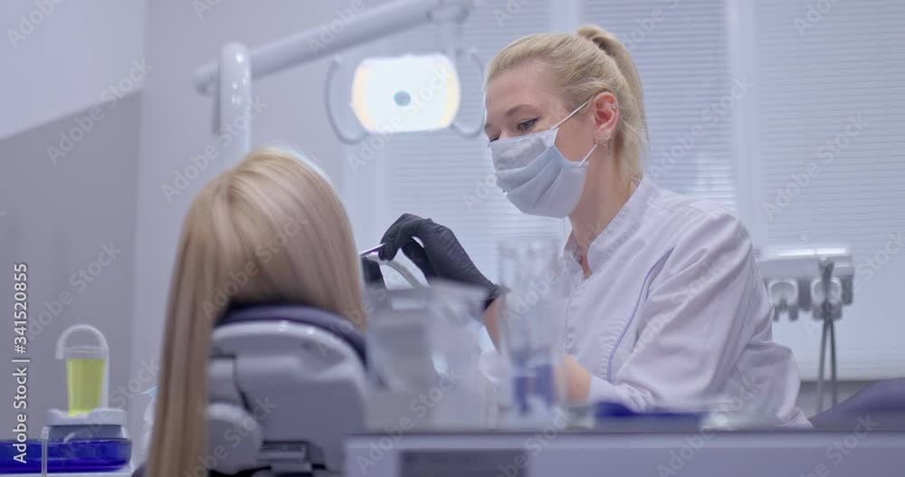 Dentist doctor in a mask and gloves. Dentist examines the patient’s teeth, begins treatment. Portrait view. Dentist doctor in a mask and gloves. Dentist examines the patient’s teeth, begins treatment. Portrait view.