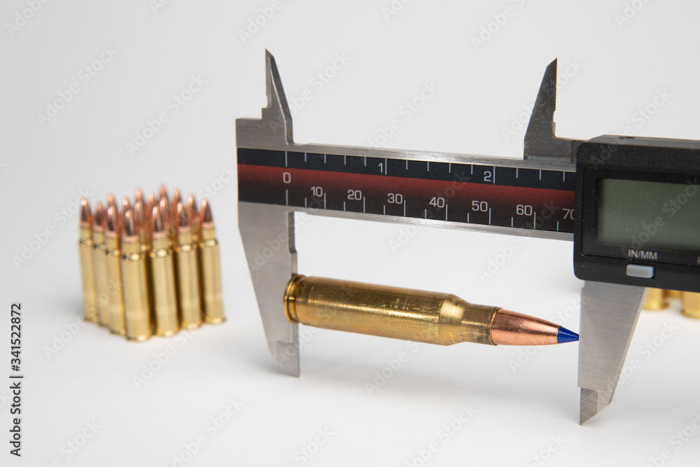 Caliper used to measure length of cartridge after seating bullet into