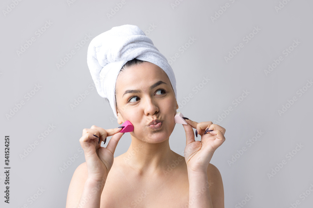 Beauty portrait of woman in white towel on head with a sponge for a body in view of a pink heart. Skincare cleansing eco organic cosmetic spa relax concept. Beauty portrait of woman in white towel on head with a sponge for a body in view of a pink heart. Skincare cleansing eco organic cosmetic spa relax concept.