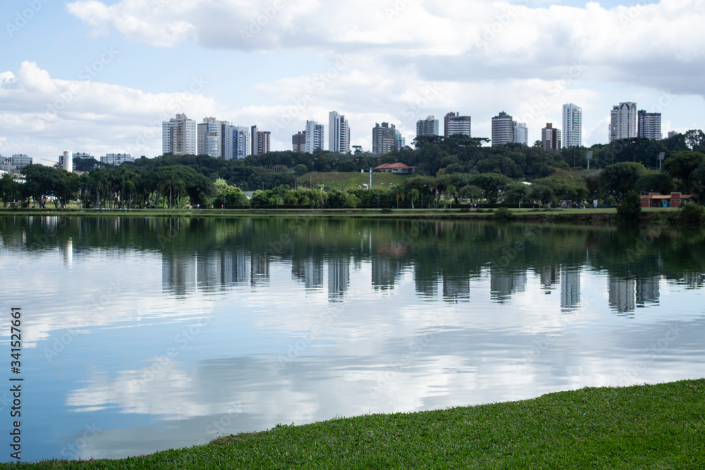 Cityscape of buildings reflected in lake and cloudy sky