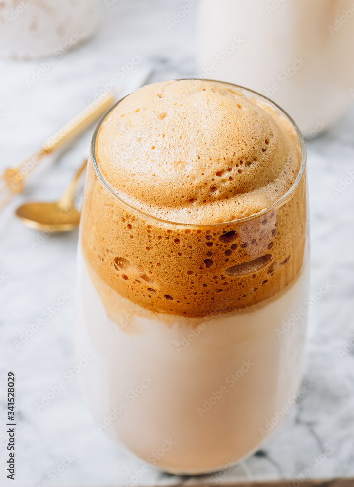 Iced frothy Dalgona Coffee, a trendy fluffy creamy whipped coffee. Korean drink latte espresso with coffee foam. made of instant coffee, sugar, hot water and milk.