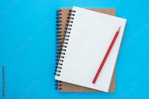 Top view above of open spiral notebook and red pencil isolated on light blue background for design a mockup. Education and business concept. flat lay