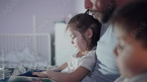 Family on self-isolation. The father reads a book to the children. Paternity. Care of children. Happy childhood. The family stays at home. Quarantine. Home school. Close-up.