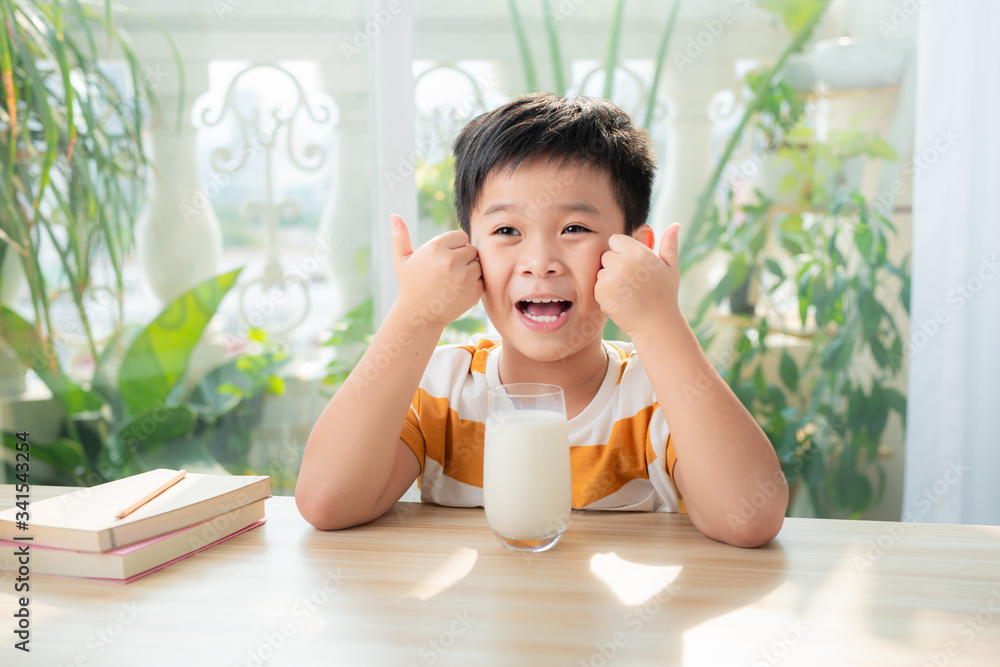 A asian boy drinking milk while sitting at desk after doing homework. E-learning and education concept. A asian boy drinking milk while sitting at desk after doing homework. E-learning and education concept.