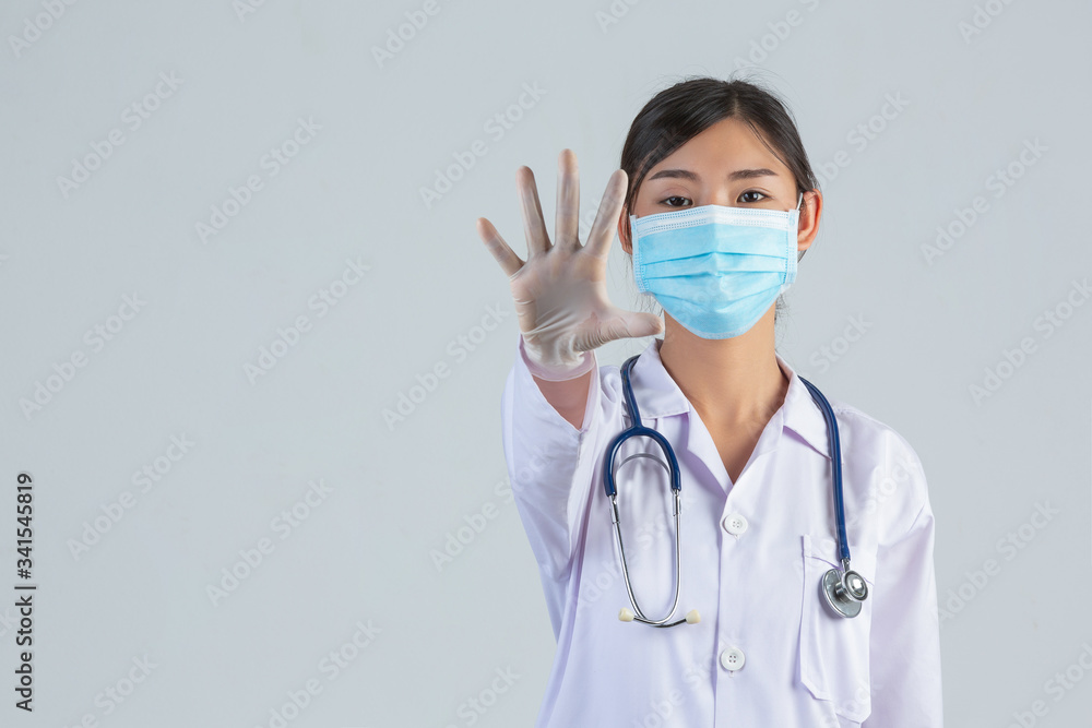 Young beautiful doctor is wearing mask while making stop hand on white background. Young beautiful doctor is wearing mask while making stop hand on white background.