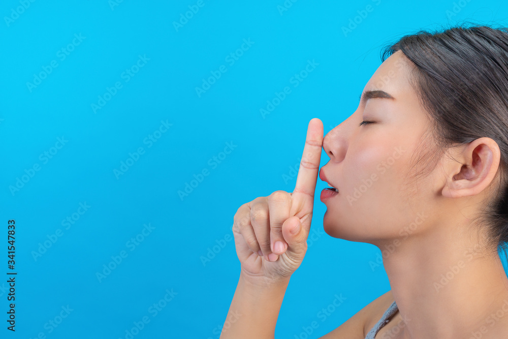 Young girl is keeping secret finger on lip in studio, blue background. Young girl is keeping secret finger on lip in studio, blue background.