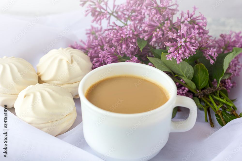 Coffee or tea with milk and marshmallows. Reading a book in the garden with a cup of coffee. Romantic still life with lilac flowers. Coffee or tea with milk and marshmallows. Reading a book in the garden with a cup of coffee. Romantic still life with lilac flowers.