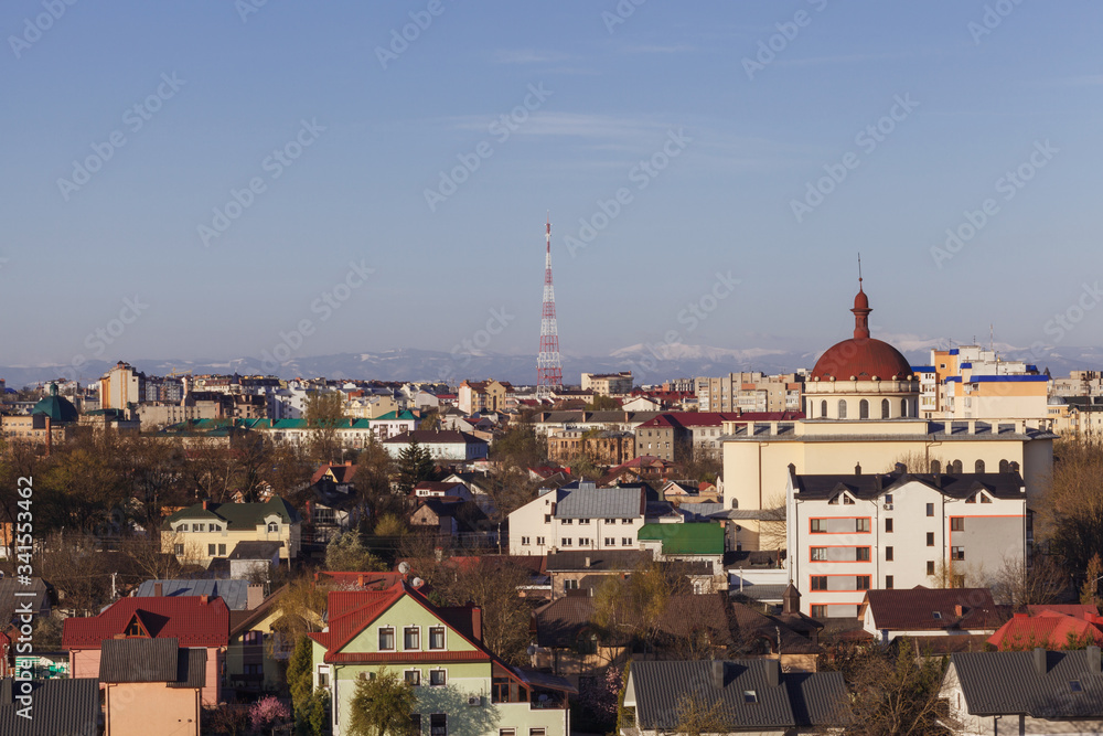 View of a small town with a church and a television tower on a background of mountains and sky