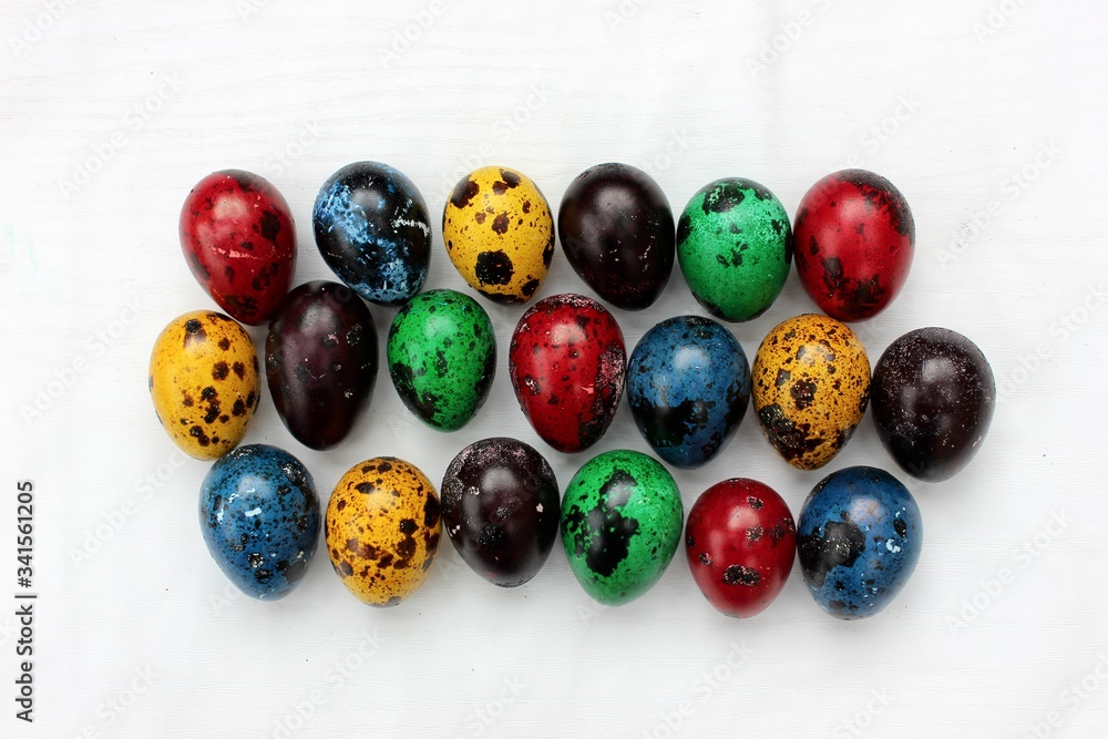 Multi-colored eggs close-up, top view. Set of easter eggs isolated on white. Easter background. Blue, red, green, yellow, purple quail eggs.