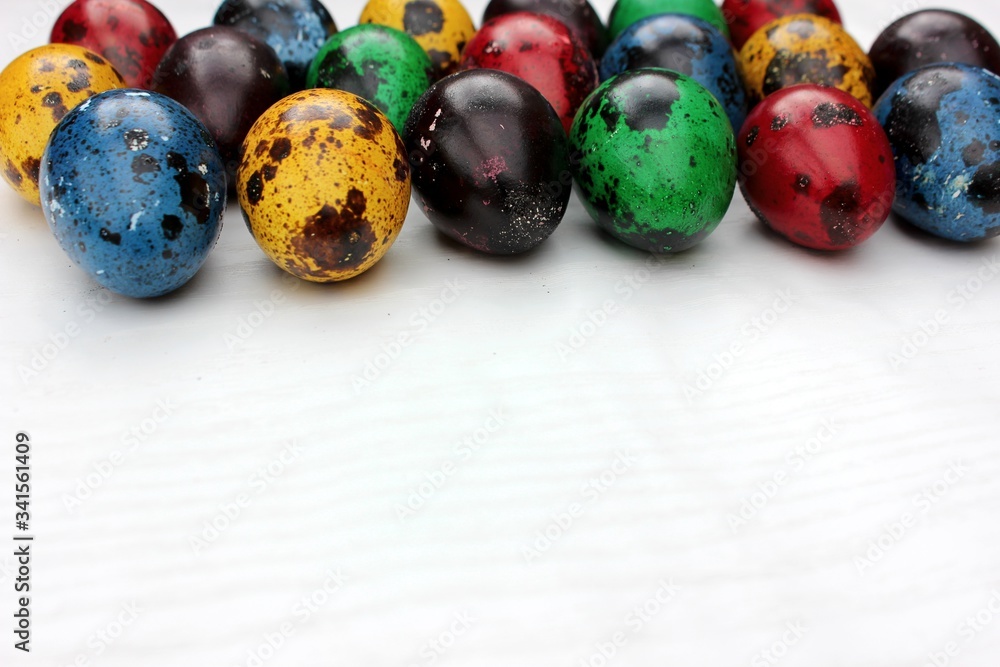 Frame of multi-colored quail eggs. Multi-colored quail Easter eggs on a white background. Multi-colored eggs are located at the top with a place for text. Dietary food.