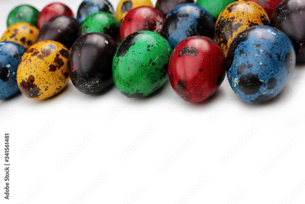 Frame of multi-colored quail eggs. Multi-colored quail Easter eggs on a white background. Multi-colored eggs are located at the top with a place for text. Dietary food.