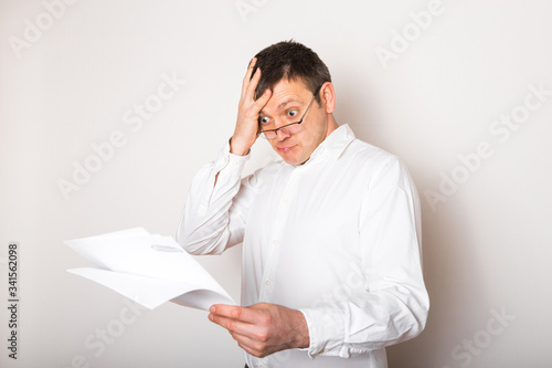Portrait of funny caucasian businessman shocked surprised with open glasses  to see financial report, bad news concept