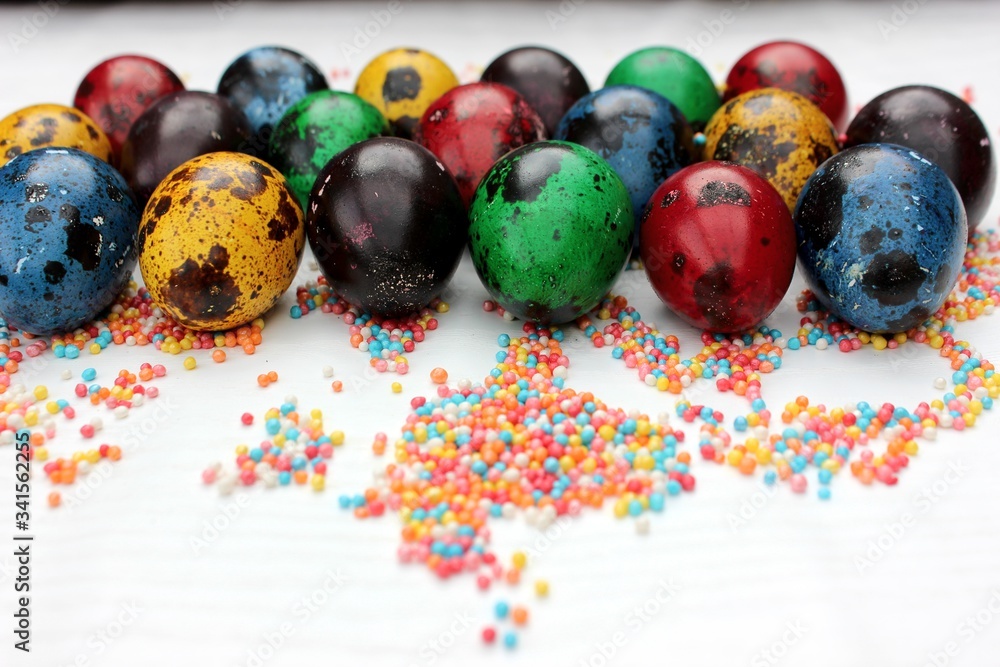 Multi-colored eggs close-up on pastry topping, top view. Set of easter eggs isolated on white. Easter background. Blue, red, green, yellow, purple quail eggs.