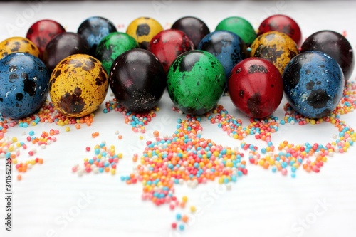 Obraz na płótnie Multi-colored eggs close-up on pastry topping, top view. Set of easter eggs isolated on white. Easter background. Blue, red, green, yellow, purple quail eggs. w salonie