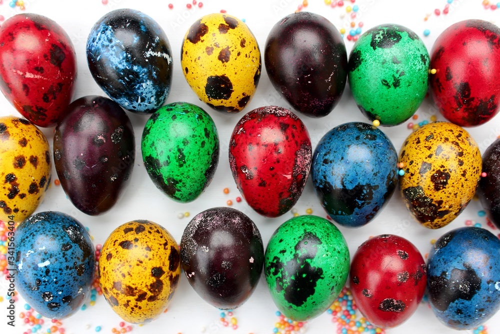 Multi-colored eggs close-up, top view. Set of easter eggs isolated on white. Easter background. Blue, red, green, yellow, purple quail eggs.