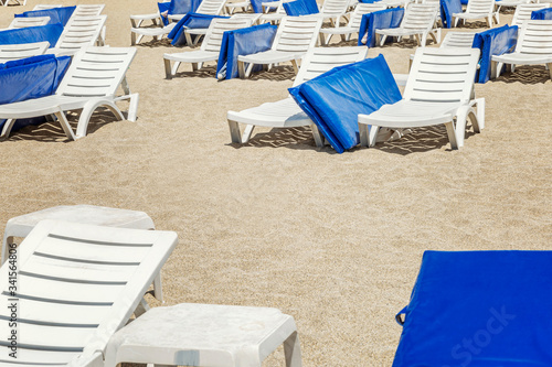 Empty deckchairs with blue mattresses on the sandy beach at the resort.