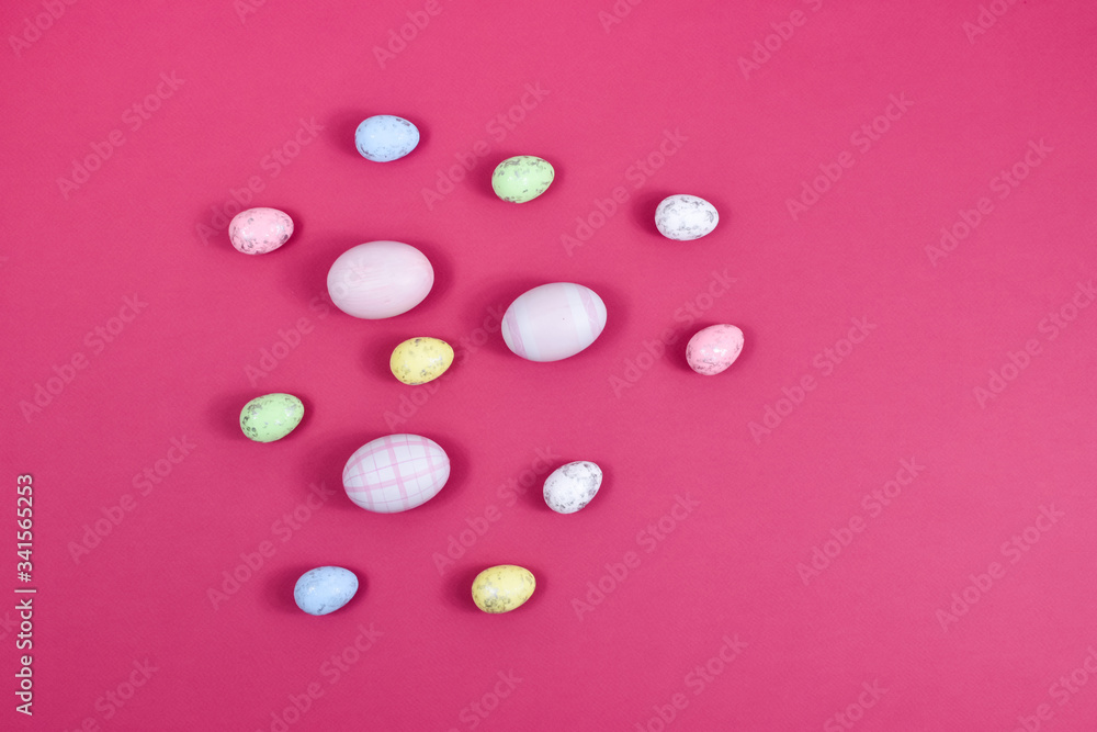 Easter concept. Easter multi-colored eggs near a basket with white flowers on a red table on a background of a white wall. Place for an inscription. For greeting cards. Easter concept. Easter multi-colored eggs near a basket with white flowers on a red table on a background of a white wall. Place for an inscription. For greeting cards.