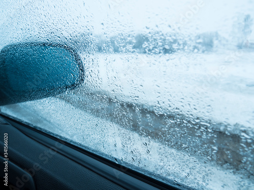 Drops of water on the side window of the car, a mirror is visible in the frame. © Popel