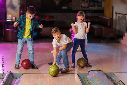 Little children playing bowling in club photo