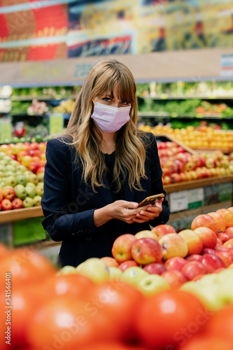 Woman in a face mask while shopping in a supermarket during coronavirus quarantine