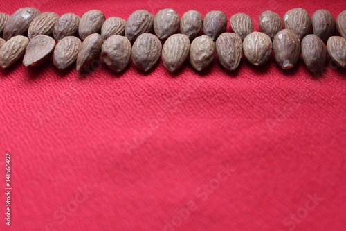 Obraz na płótnie Almonds lined with a line on a red background. Almonds closeup with place for text. Nuts and dried fruits, healthy nutrition. w salonie