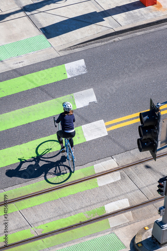 Cuadro en lienzo Woman in a sports uniform rides a bicycle across the road along the green lane f