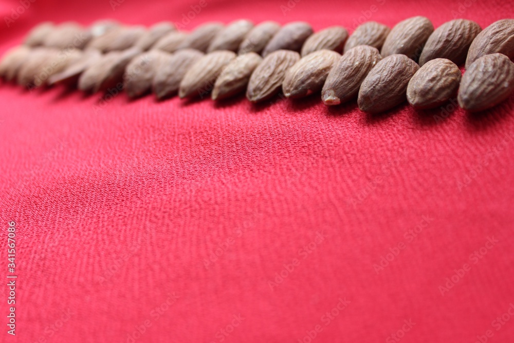 Almonds lined with a line on a red background. Almonds closeup with place for text. Nuts and dried fruits, healthy nutrition.