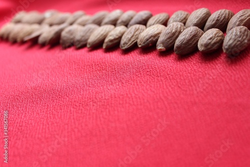 Obraz na płótnie Almonds lined with a line on a red background. Almonds closeup with place for text. Nuts and dried fruits, healthy nutrition. w salonie