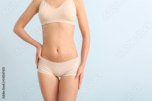Beautiful young woman in underwear on color background. Concept of cellulite