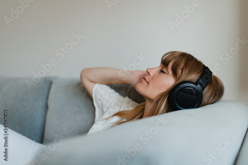Woman listening to music  during coronavirus quarantine on a couch