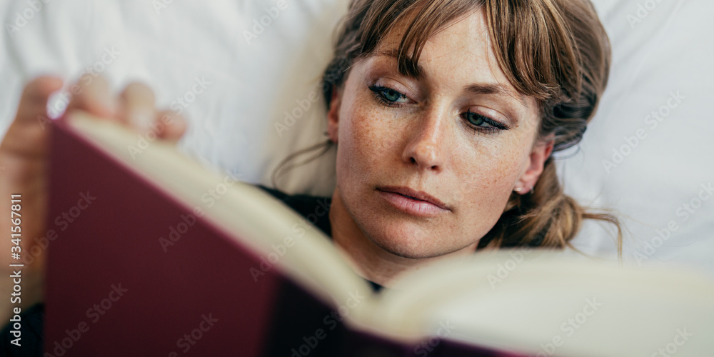 Woman reading a book on a bed during coronavirus quarantine Woman reading a book on a bed during coronavirus quarantine