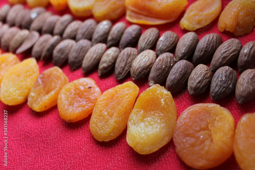 Almonds and dried apricots lined with a line on a red background. Almonds and dried apricots close-up with place for text. Nuts and dried fruits, healthy nutrition.