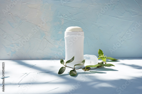 Foto White bottle of dry deodorantat and green branch at blue concrete wall