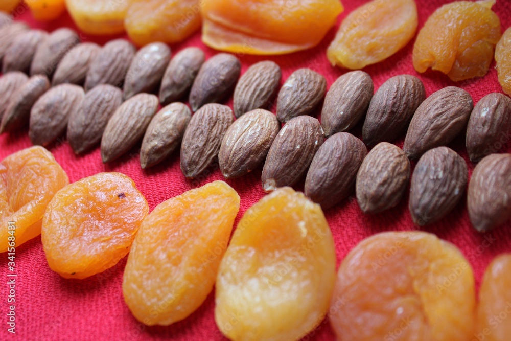 Almonds and dried apricots lined with a line on a red background. Almonds and dried apricots close-up with place for text. Nuts and dried fruits, healthy nutrition.