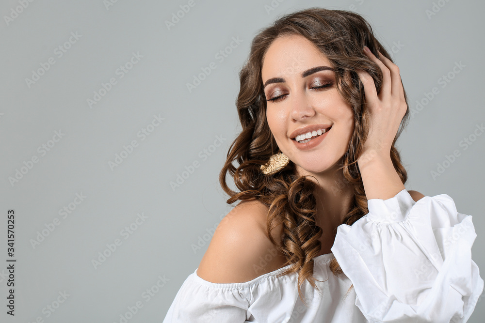 Beautiful young woman with curly hair on grey background Beautiful young woman with curly hair on grey background