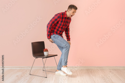 Foto Young man and chair with cactus near color wall