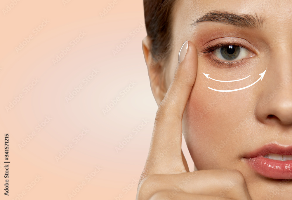 beauty, makeup and lifting concept - close up of beautiful young woman face with arrows under eye area over beige background - obrazy, fototapety, plakaty 
