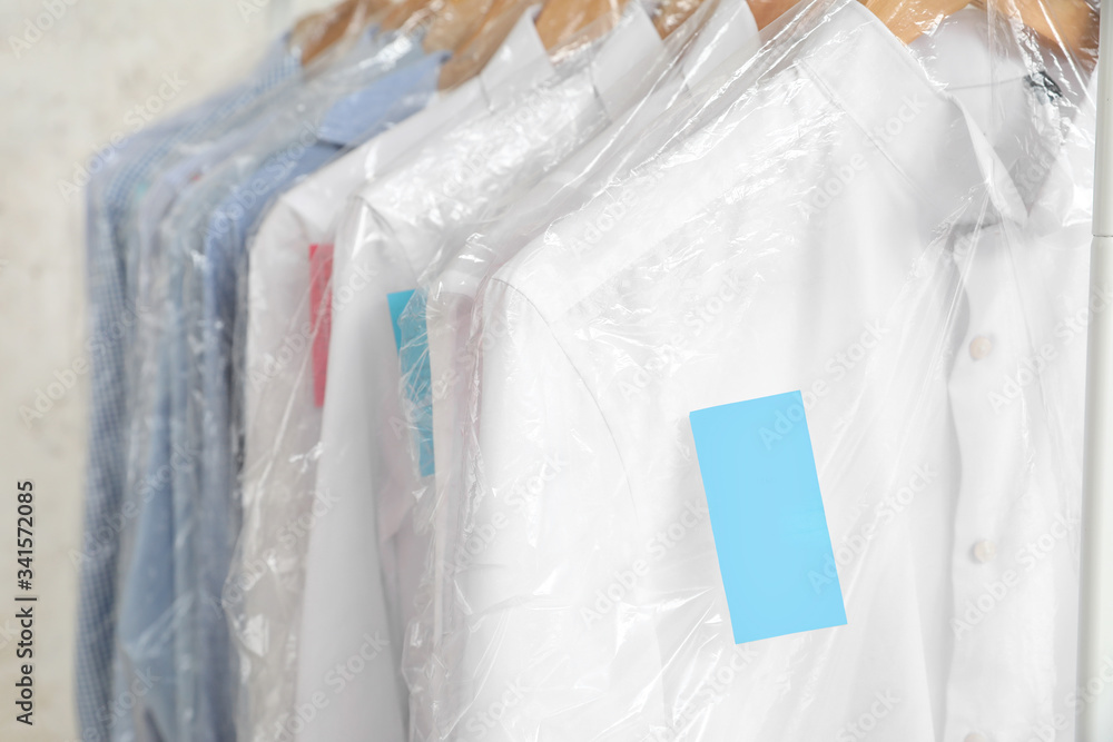 Rack with clothes after dry-cleaning on light background, closeup Rack with clothes after dry-cleaning on light background, closeup