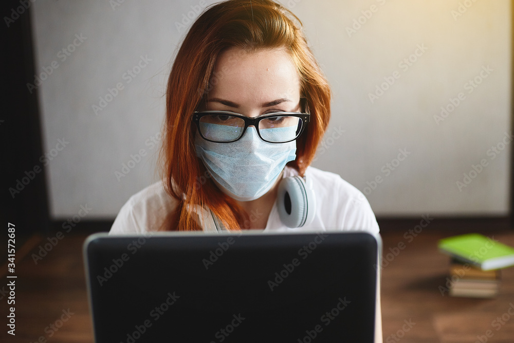 Woman working from home wearing protective mask. Student in quarantine for coronavirus wearing protective mask. Working from home