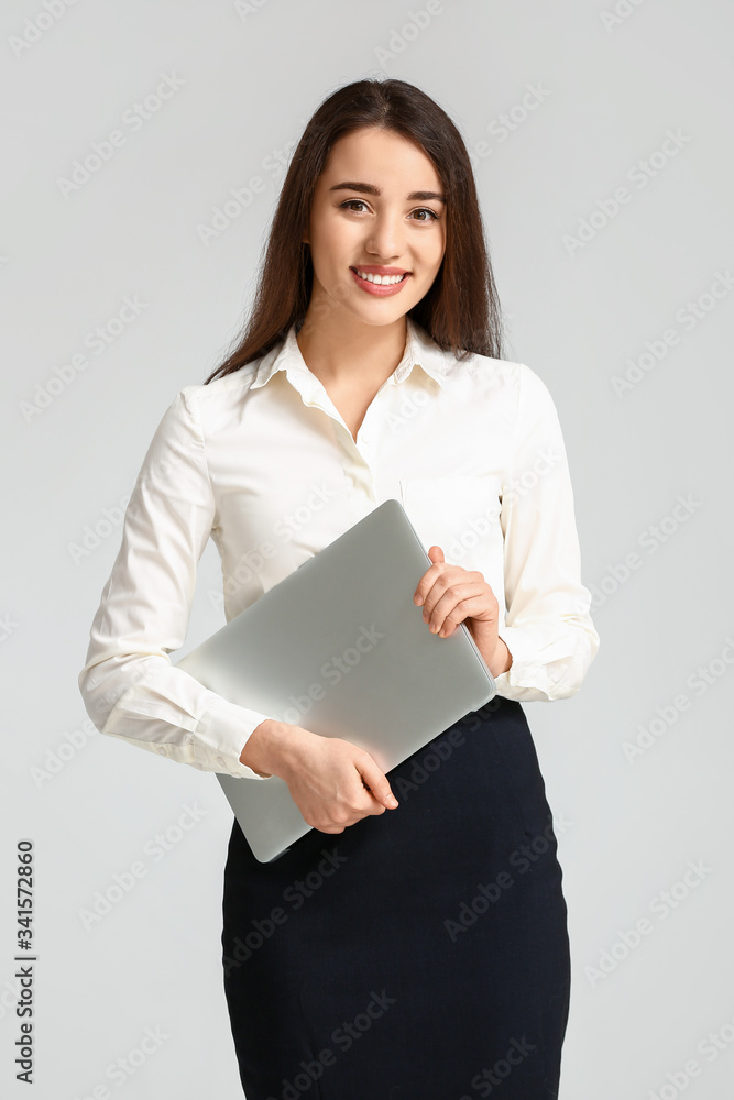 Portrait of beautiful young businesswoman with laptop on light background Portrait of beautiful young businesswoman with laptop on light background