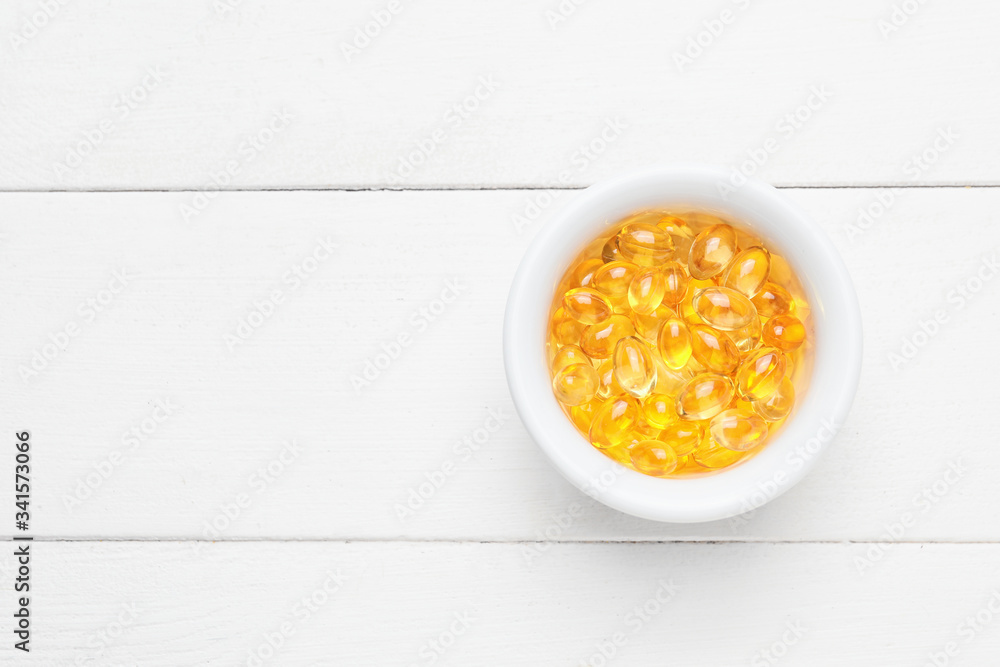 Bowl of fish oil capsules on white wooden background Bowl of fish oil capsules on white wooden background