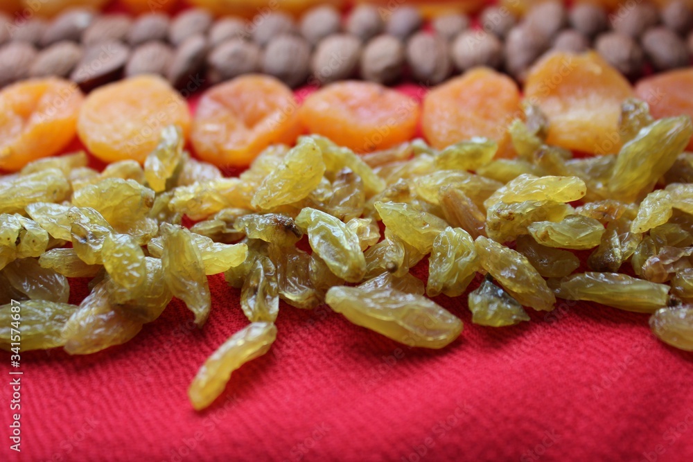 Assortment of nuts,dried fruits and seeds on a wood background.Dried fruits and nuts, symbols of judaic holiday Tu Bishvat. Almonds, raisins and dried apricots laid out by a line on a red background.