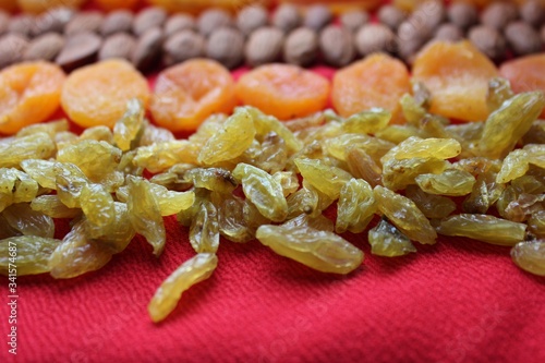 Obraz na płótnie Assortment of nuts,dried fruits and seeds on a wood background.Dried fruits and nuts, symbols of judaic holiday Tu Bishvat. Almonds, raisins and dried apricots laid out by a line on a red background. w salonie